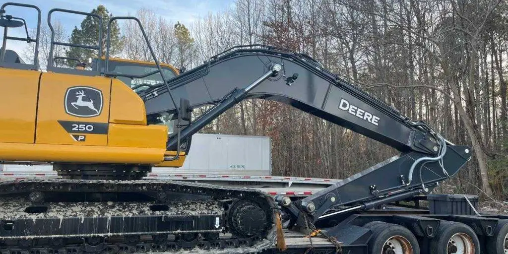A tracked excavator chained down on a lowboy trailer