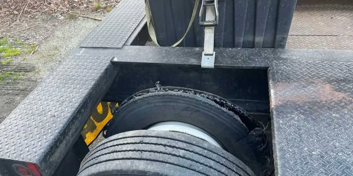 A trailer deck with spare wheels strapped down