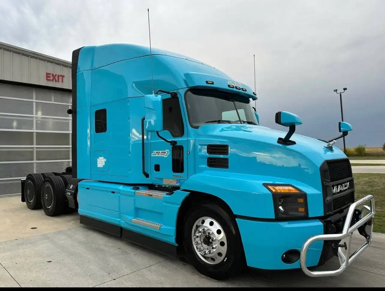 A light blue Mack Anthem sleeper tractor outside the workshop