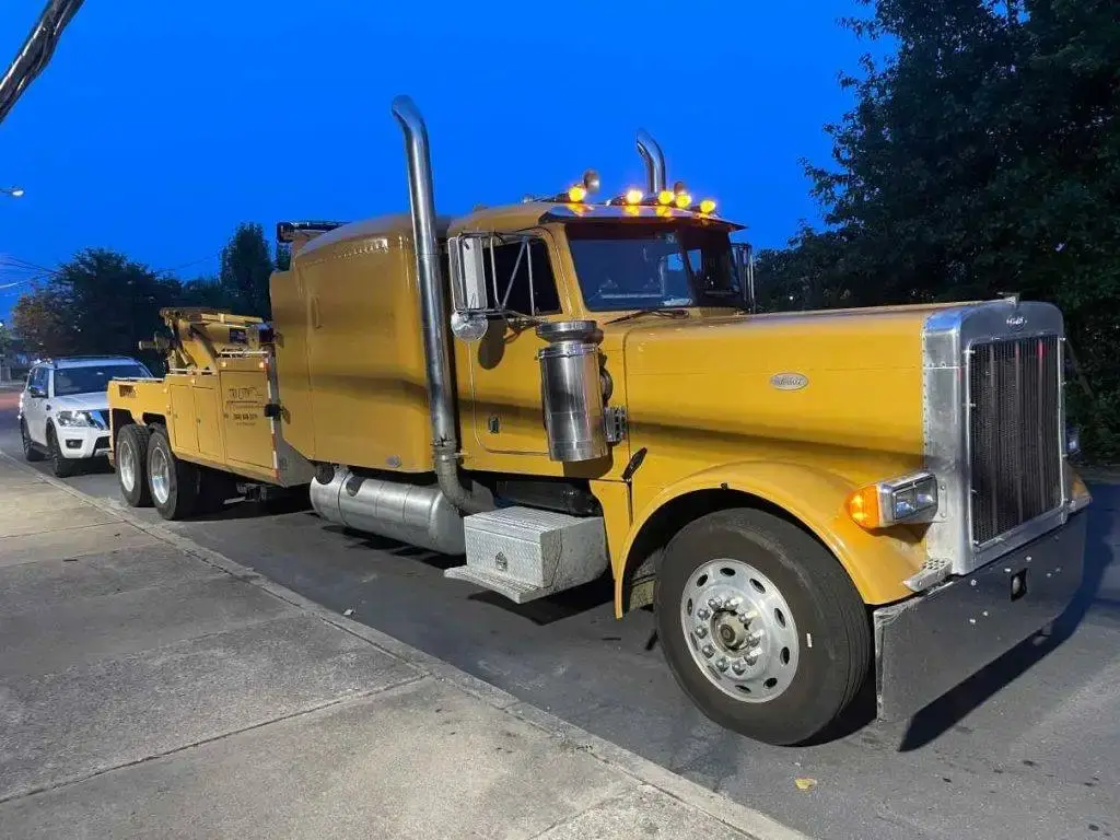 The wrecker hitched to a vehicle at dusk